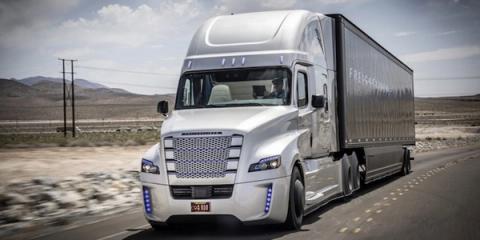 Silver Freightliner Inspiration autonomous semi-truck driving on a desert highway