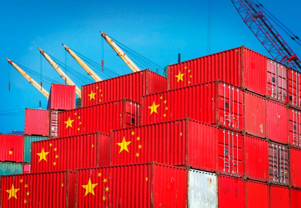 Stacks of red shipping containers bearing China's yellow stars, with port cranes against a blue sky.