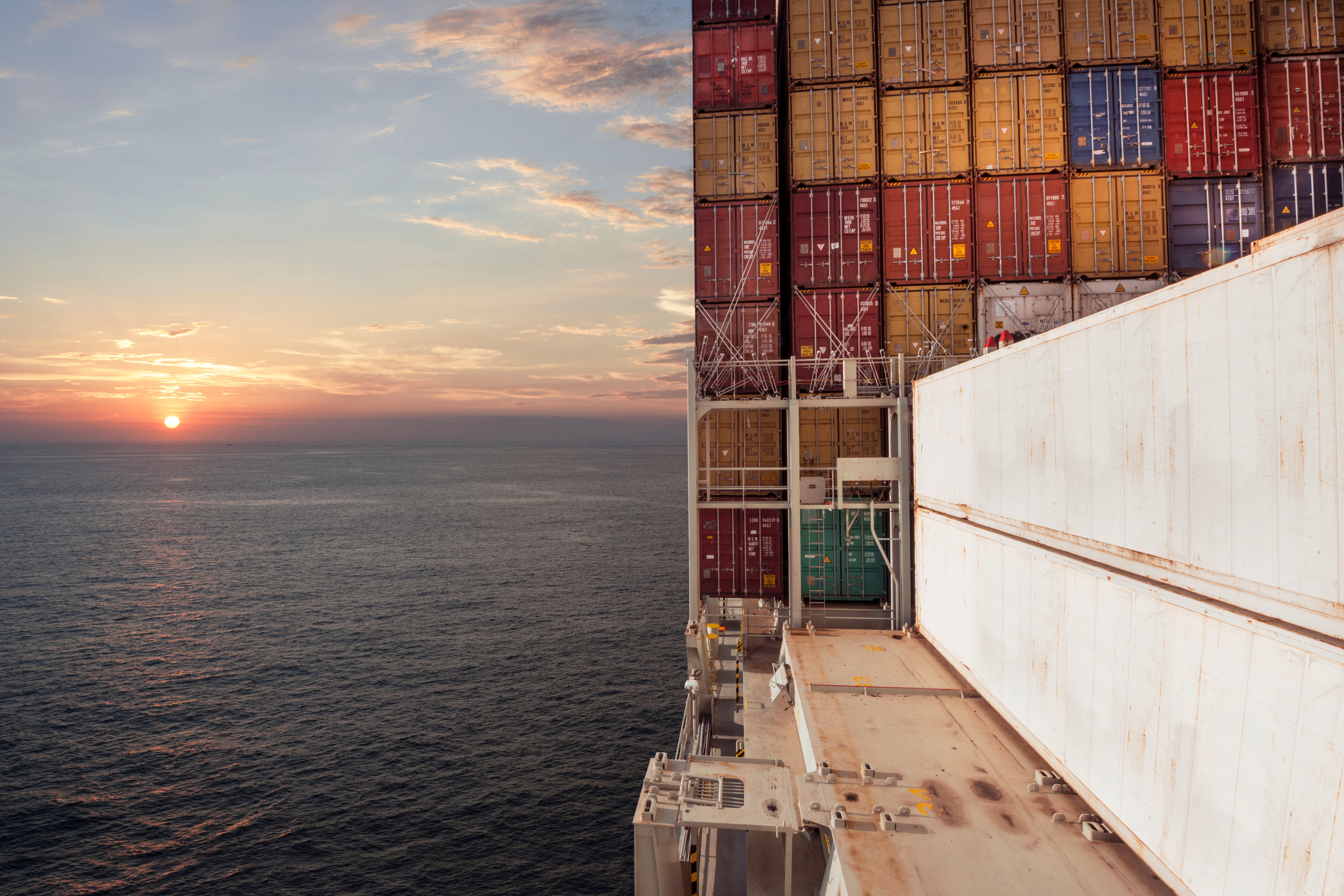 Cargo ship deck loaded with stacked shipping containers at sea.