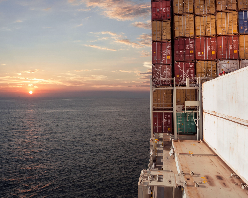 Cargo ship deck loaded with stacked shipping containers at sea.