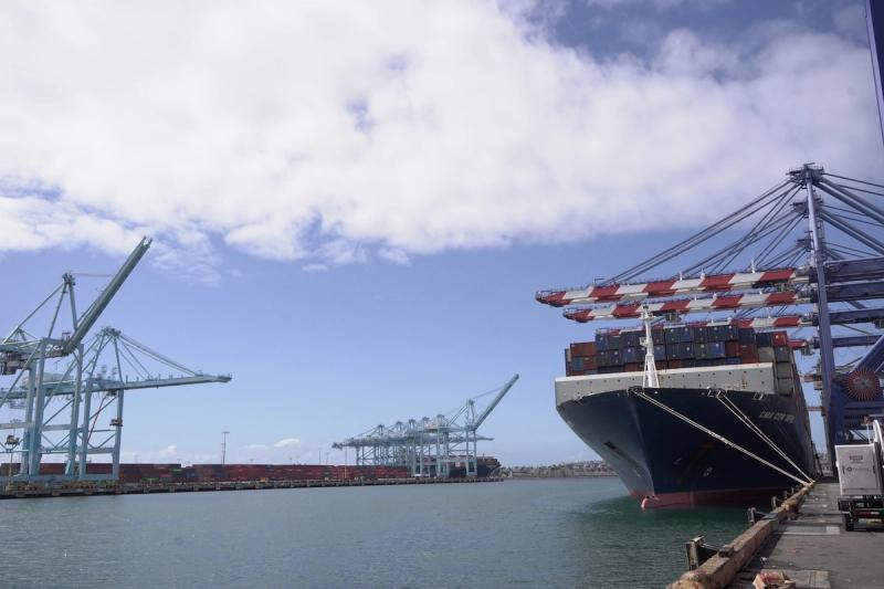 CMA CGM container ship docked under cranes at a port with more gantry cranes along the quay
