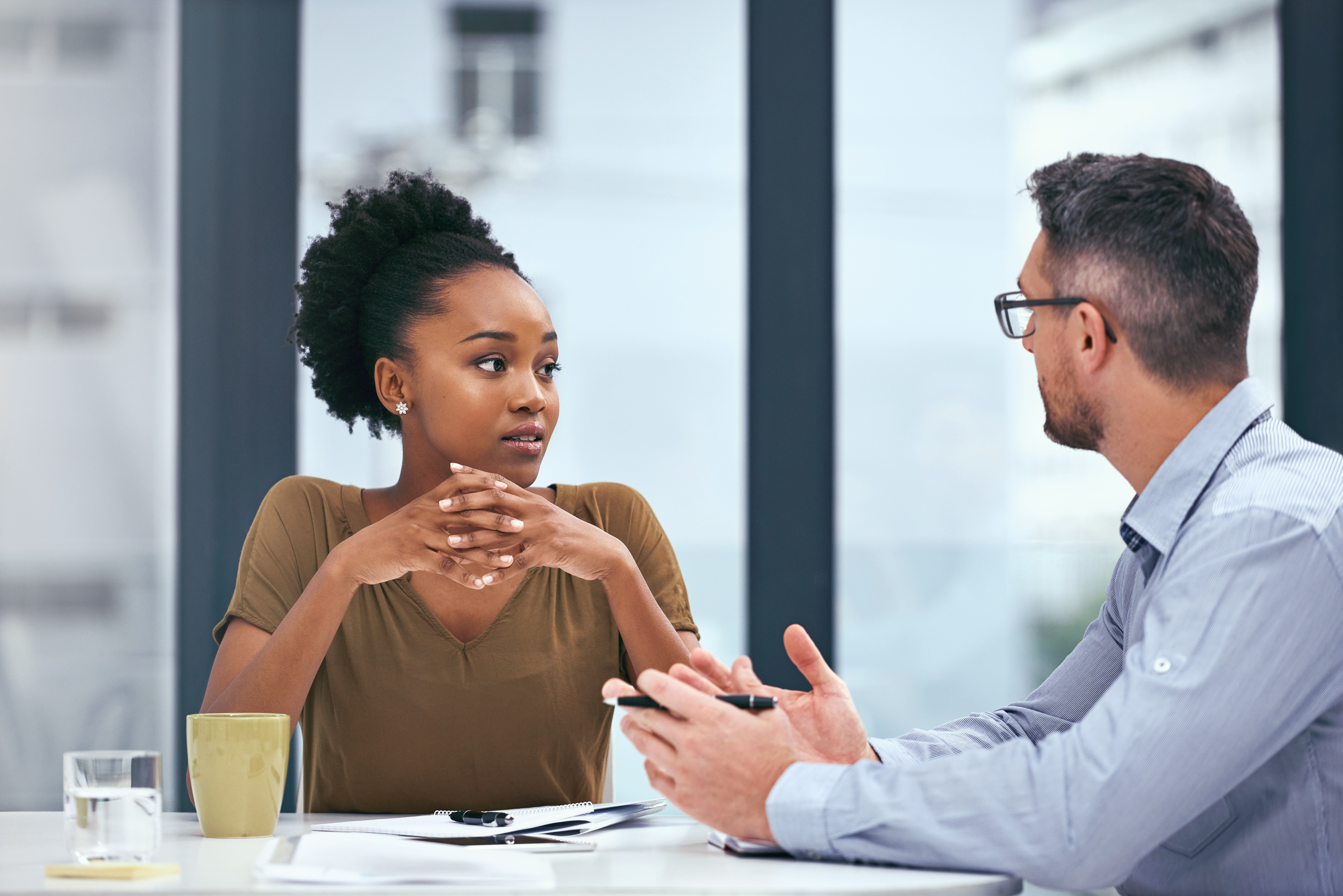 Two colleagues in conversation across an office desk