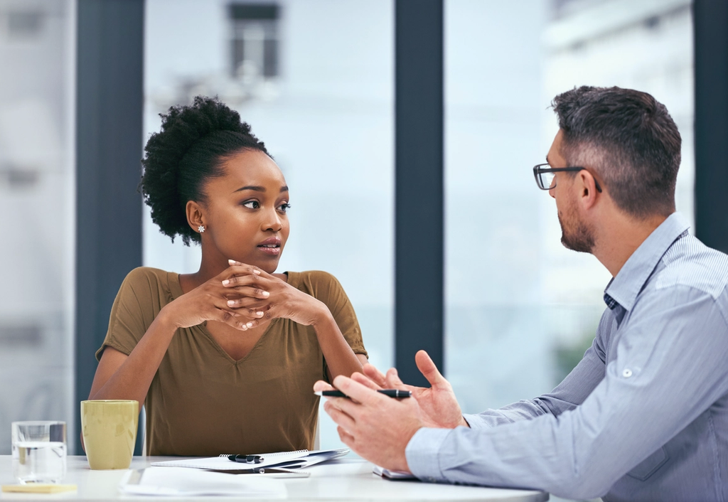 Two colleagues in conversation across an office desk