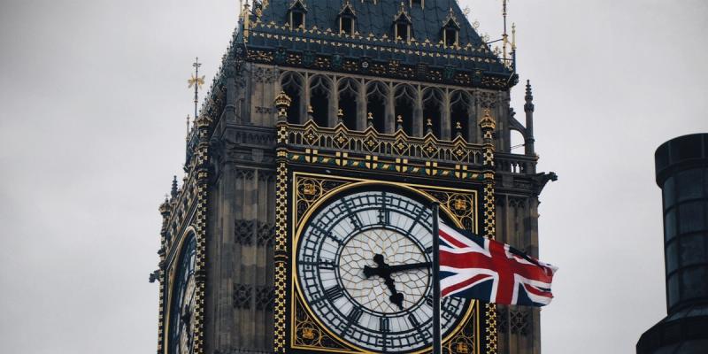 Close-up of Big Ben clock tower with a Union Jack flag flying in front under a grey sky