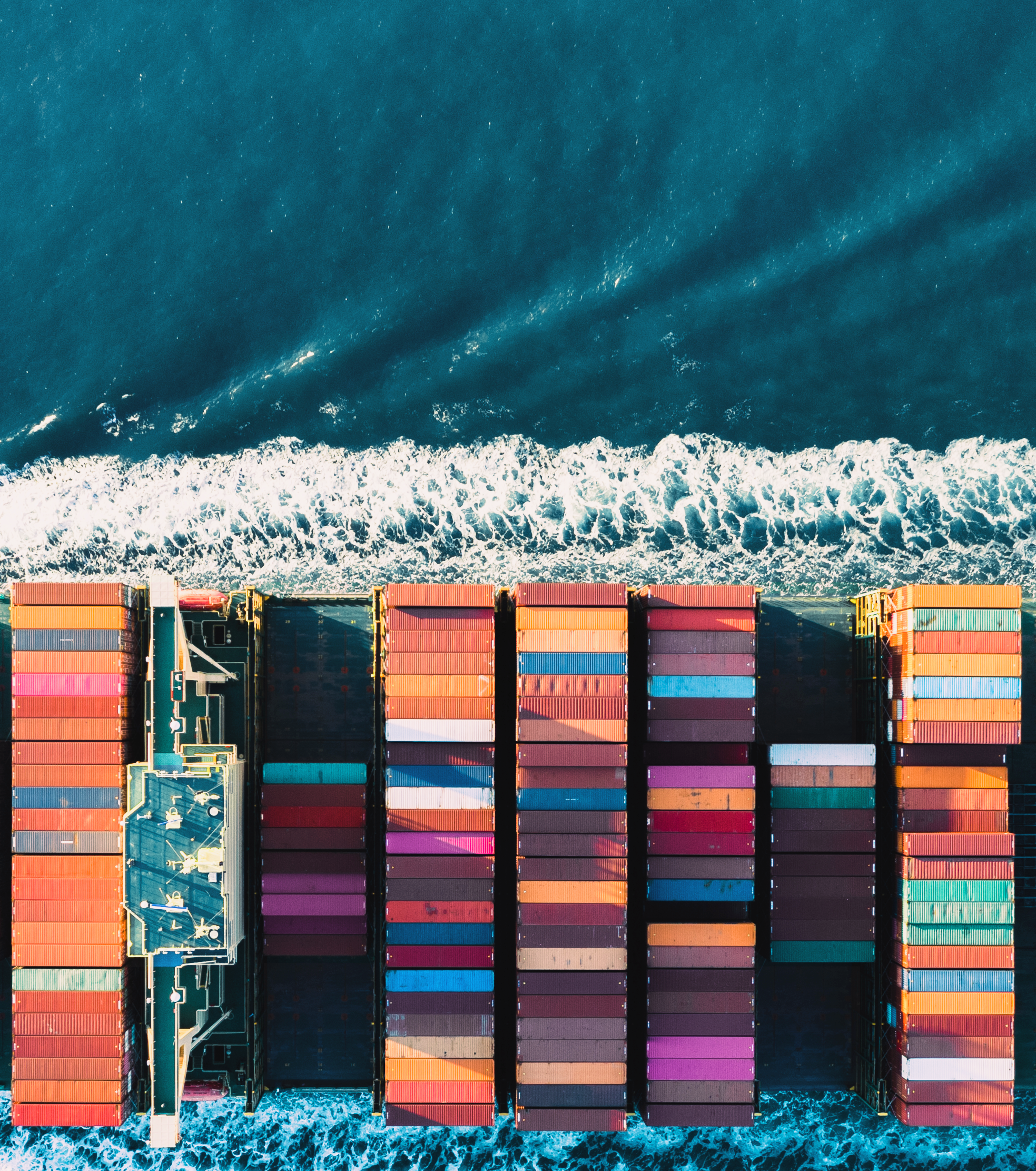 Cargo containers loaded on a ship docked at a beach shoreline with waves.
