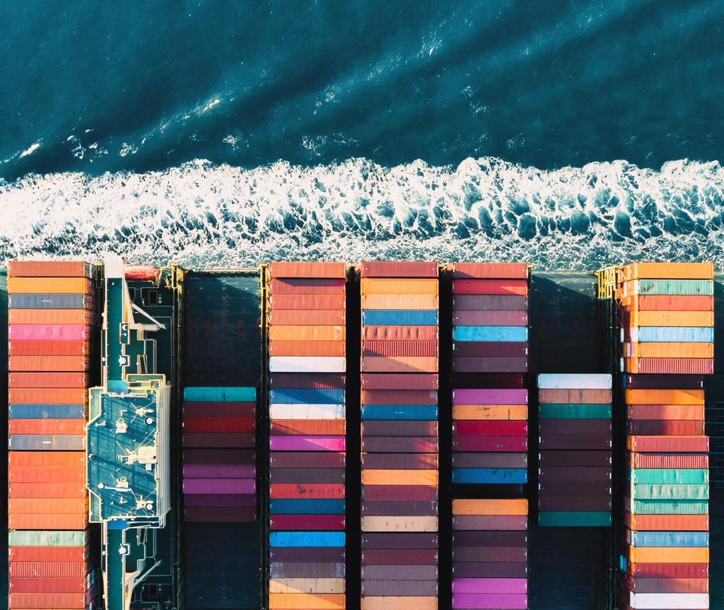 Cargo containers loaded on a ship docked at a beach shoreline with waves.
