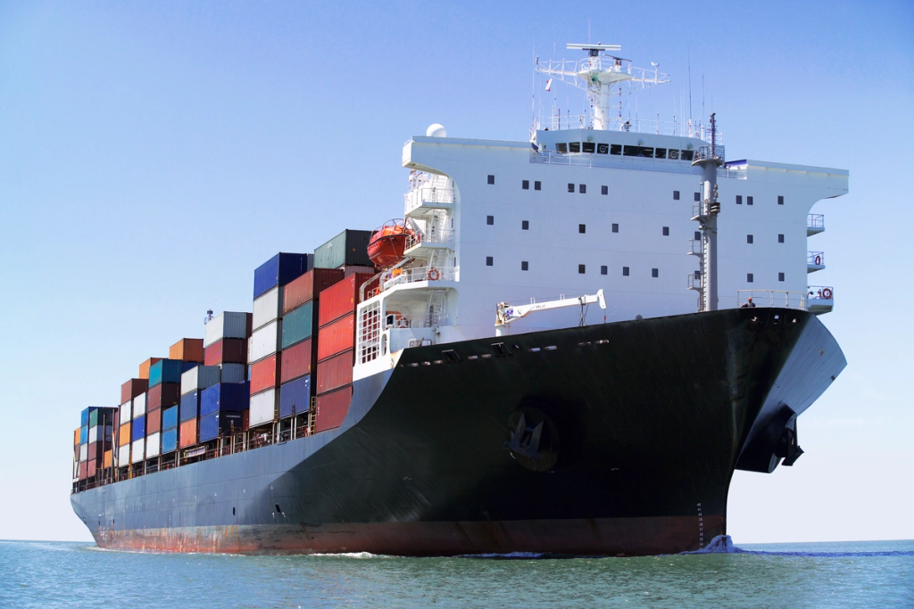 Cargo ship loaded with shipping containers cruising through open water.