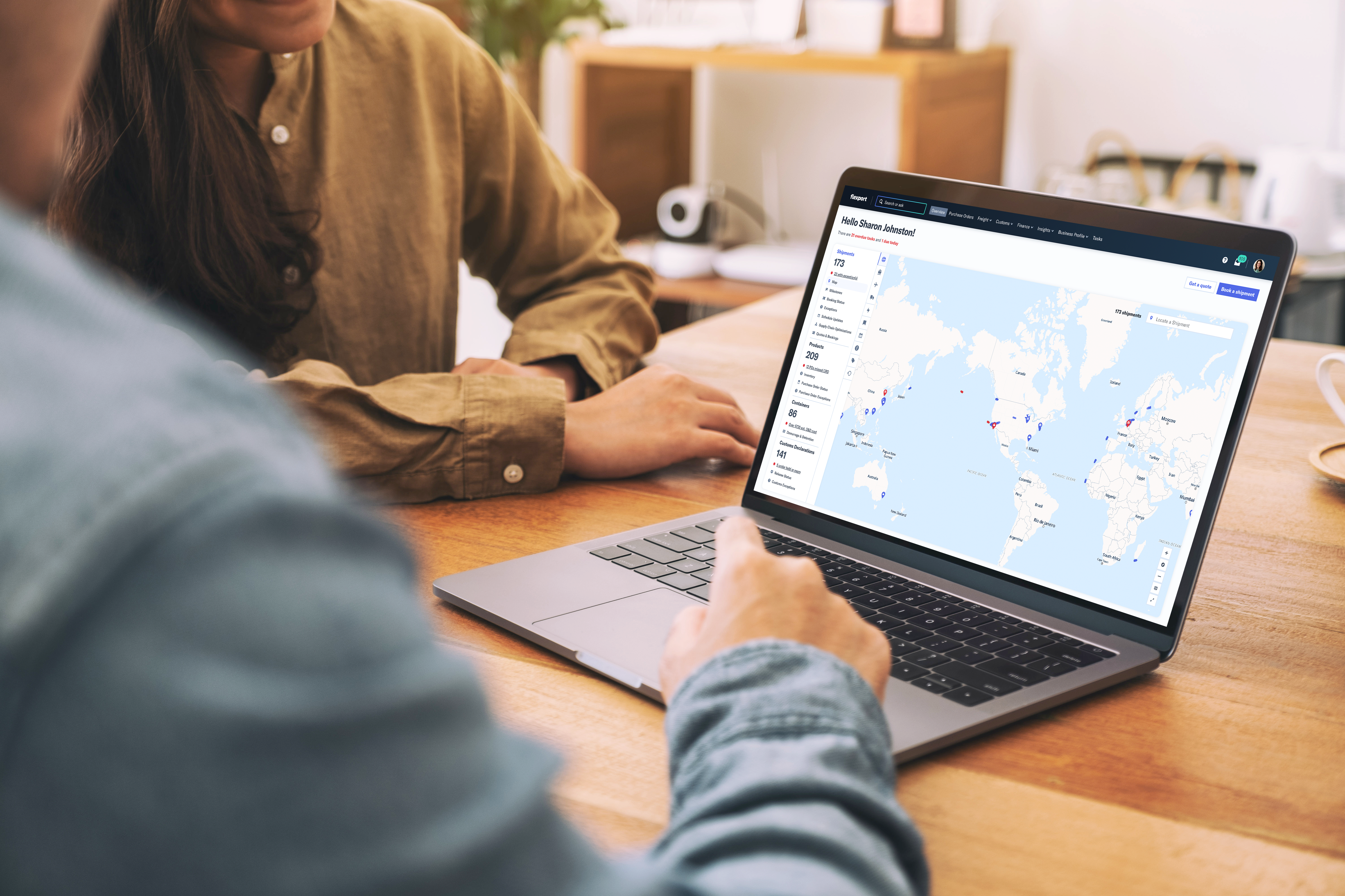 Two people review a world map dashboard on a laptop during a collaborative work session.