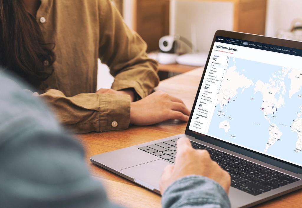 Two people review a world map dashboard on a laptop during a collaborative work session.