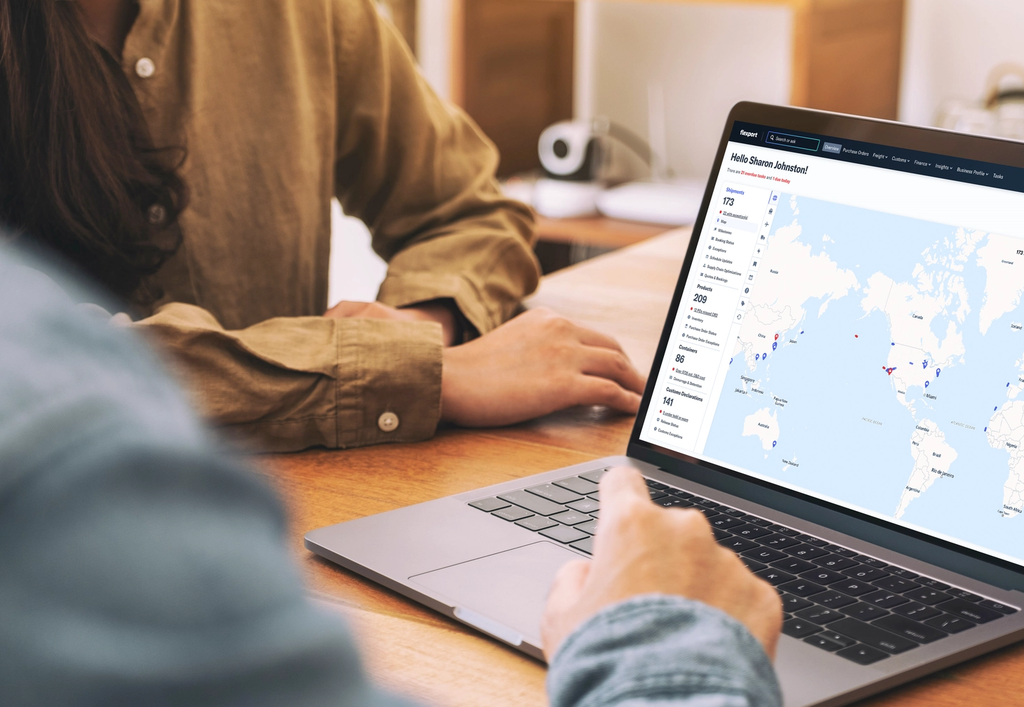Two people review a world map dashboard on a laptop during a collaborative work session.