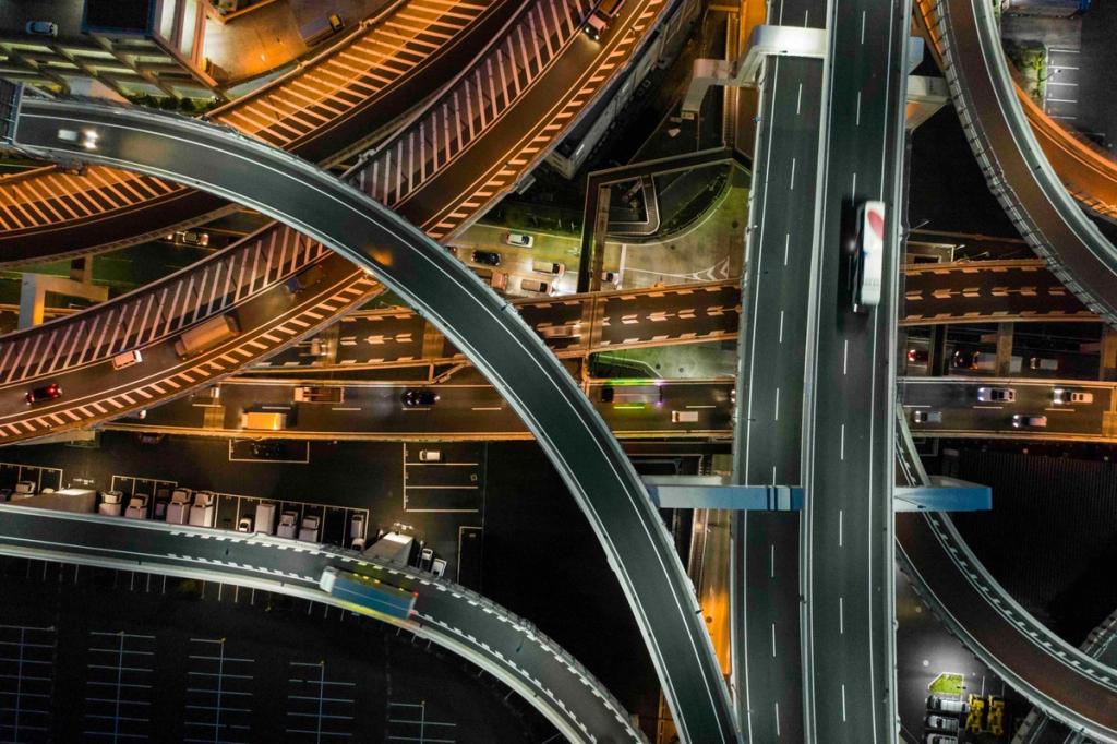 Aerial night view of an illuminated multi-level highway interchange with a truck crossing an overpass.