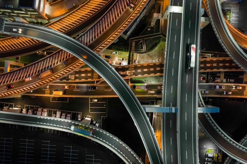 Aerial night view of an illuminated multi-level highway interchange with a truck crossing an overpass.