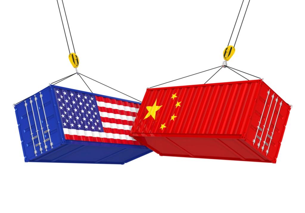 Two shipping containers hang from crane hooks, painted with the US flag and the Chinese flag.