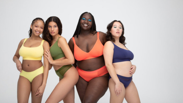 Four diverse women of different body types and skin tones modeling colorful two-piece swimwear against a plain gray background