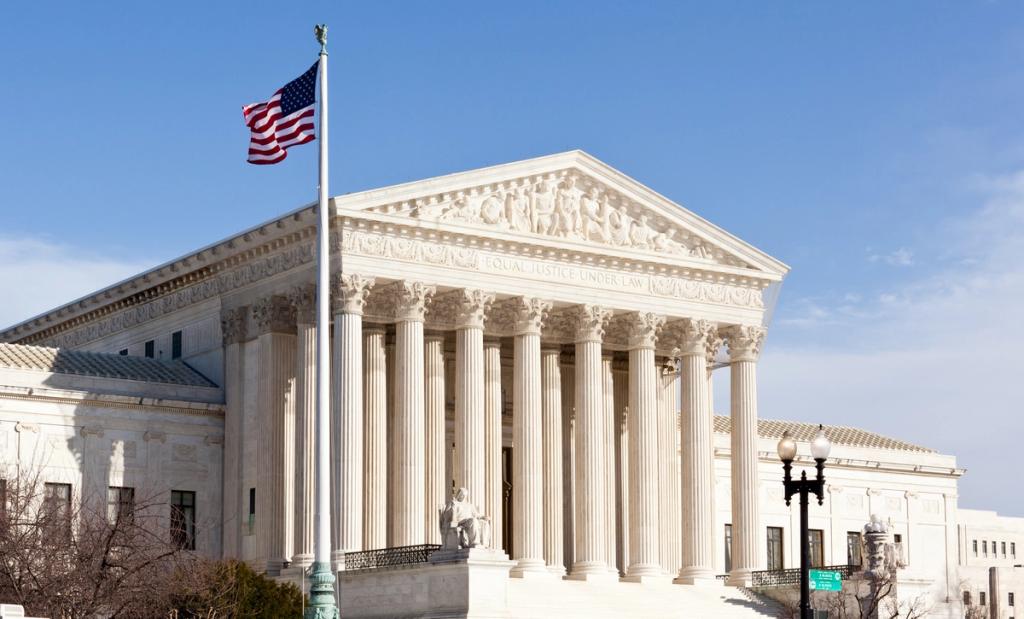 U.S. Supreme Court building with columns, "Equal Justice Under Law" inscription and American flag.