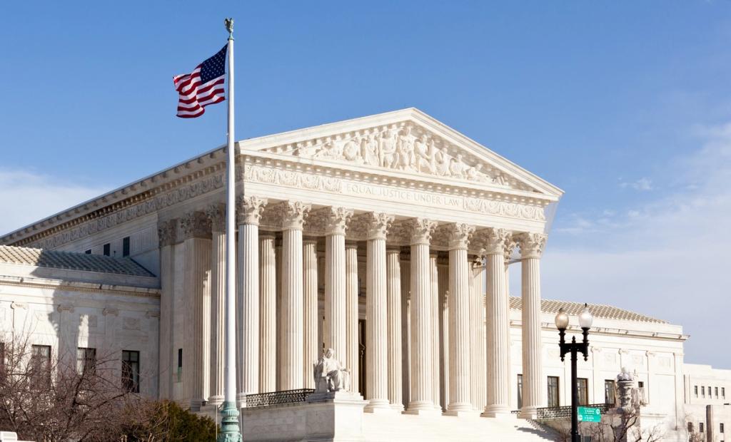 U.S. Supreme Court building with columns, "Equal Justice Under Law" inscription and American flag.