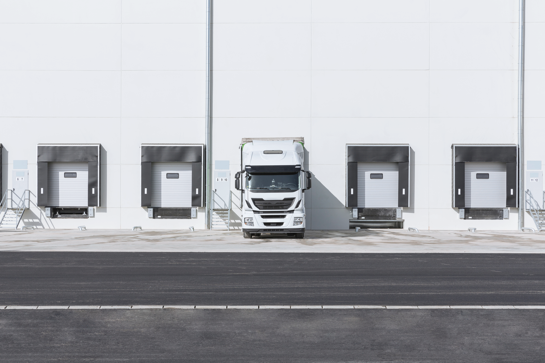 A delivery truck parked at loading dock bays with cargo doors aligned for loading.