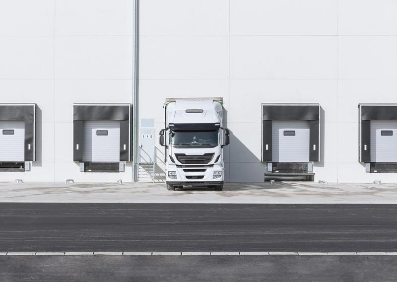 A delivery truck parked at loading dock bays with cargo doors aligned for loading.