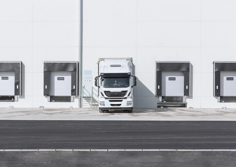 A delivery truck parked at loading dock bays with cargo doors aligned for loading.