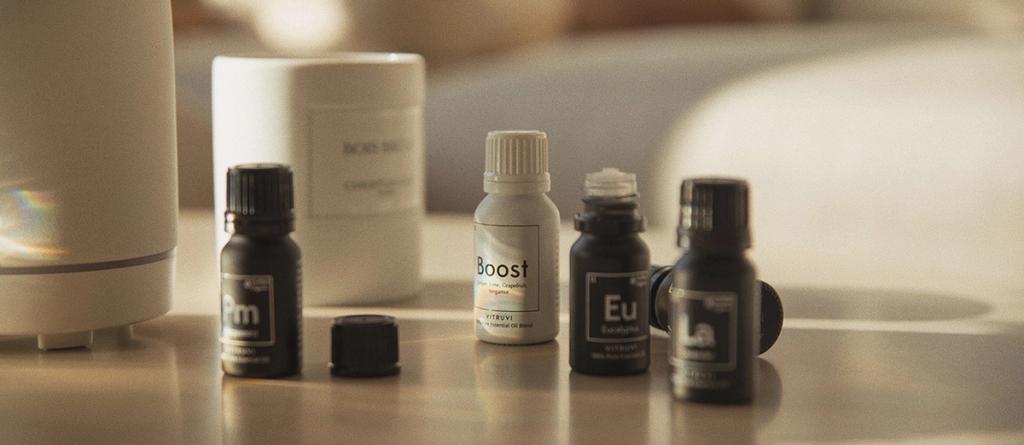Vitruvi essential oil bottles including Boost and Eucalyptus beside a white ceramic diffuser