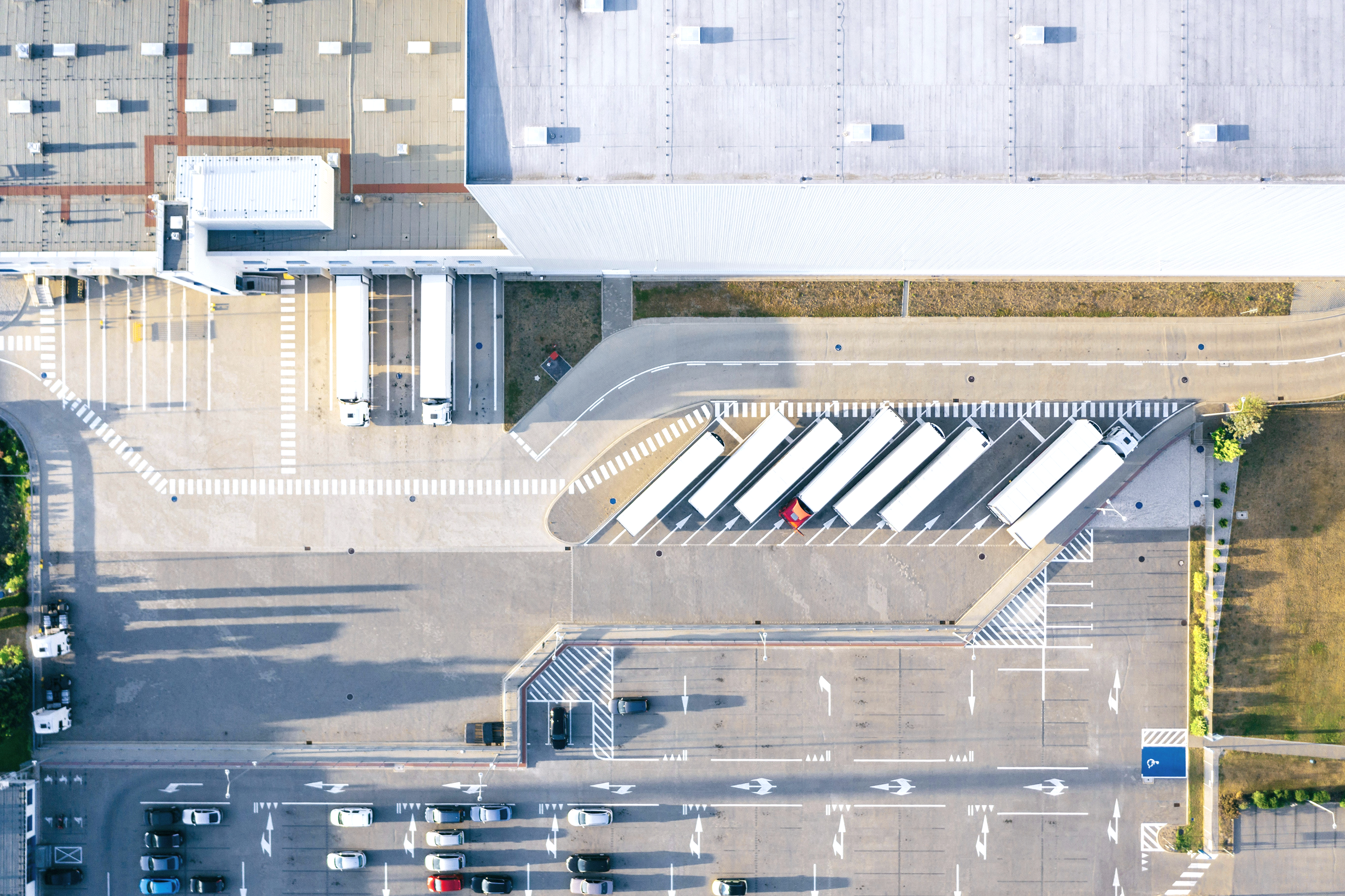 Aerial view of a parking lot with zebra crossing and buildings along the street.