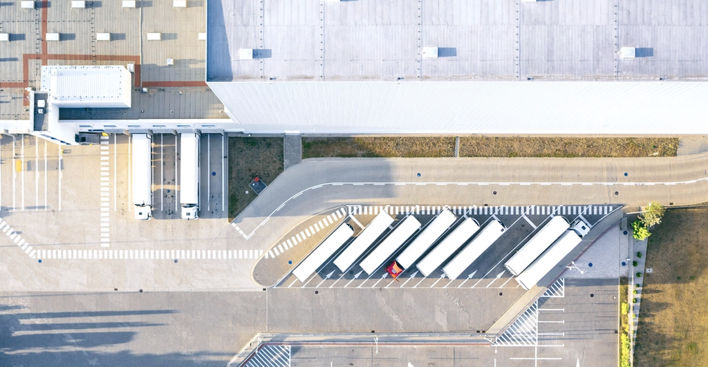 Aerial view of a parking lot with zebra crossing and buildings along the street.