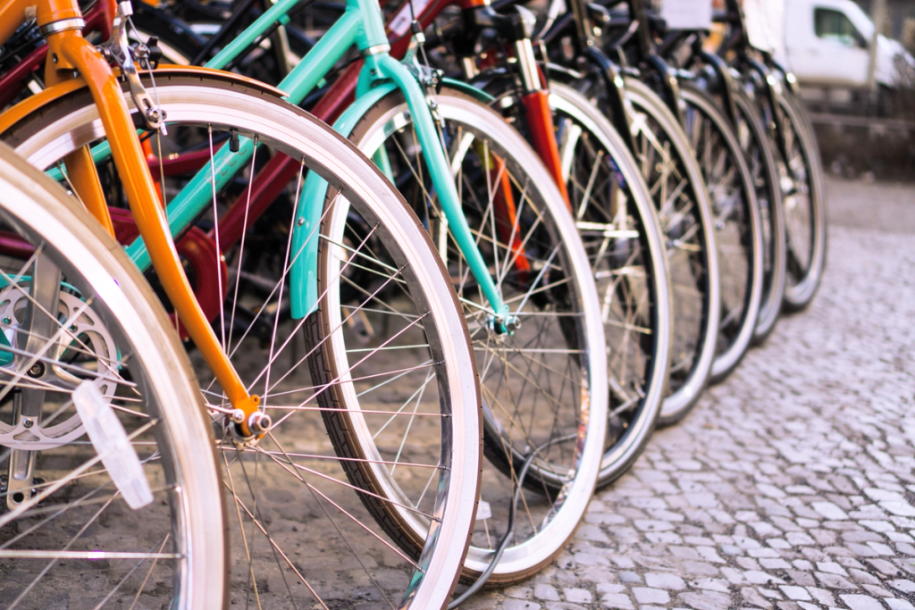 Row of colorful bicycle wheels and frames lined up on a cobblestone street