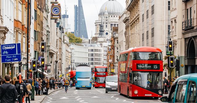 Busy London street with a red double-decker bus, traffic and pedestrians near St Paul's Cathedral dome