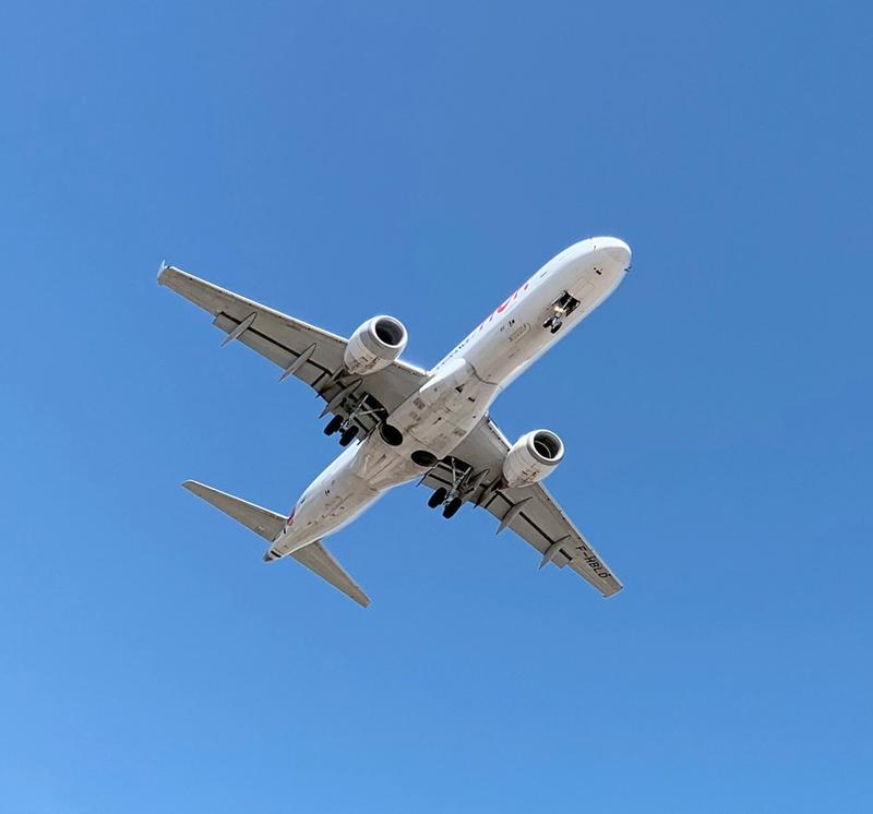Commercial airplane in flight viewed from below against clear sky.