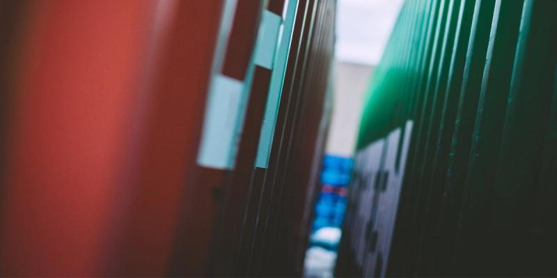Close-up of a narrow gap between stacked red and green shipping containers with shallow focus