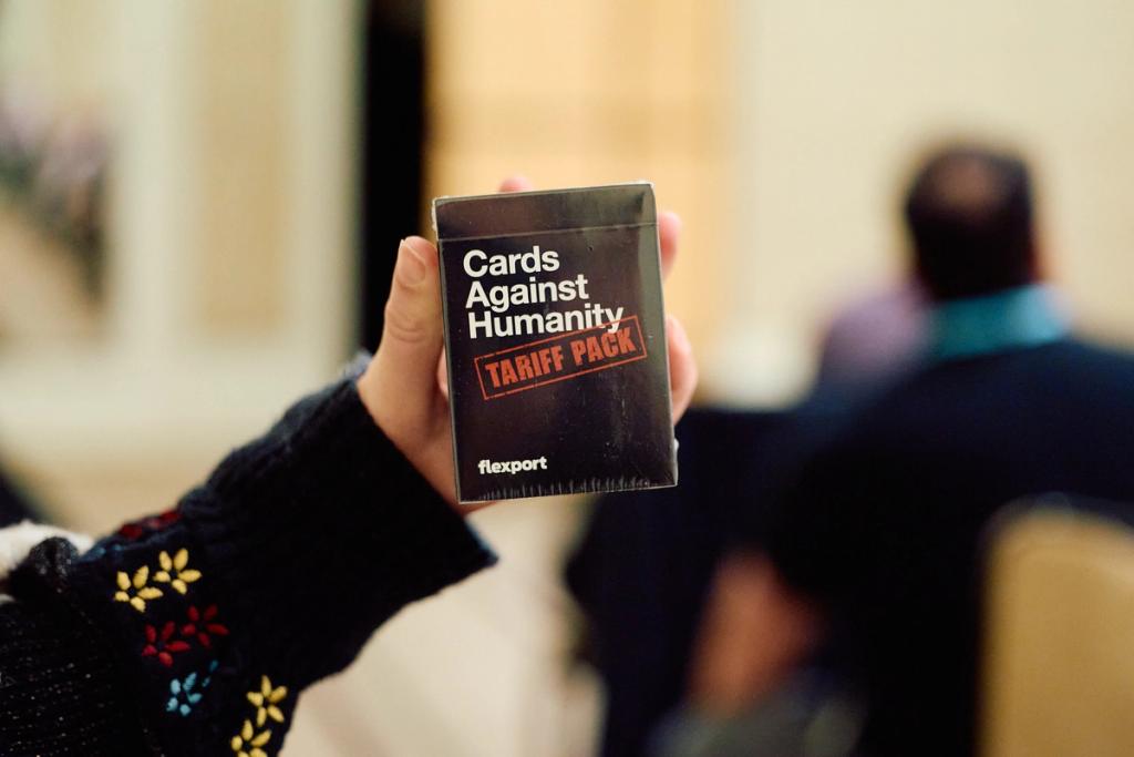 Hand holds a black Flexport "Cards Against Humanity Tariff Pack" box at an event