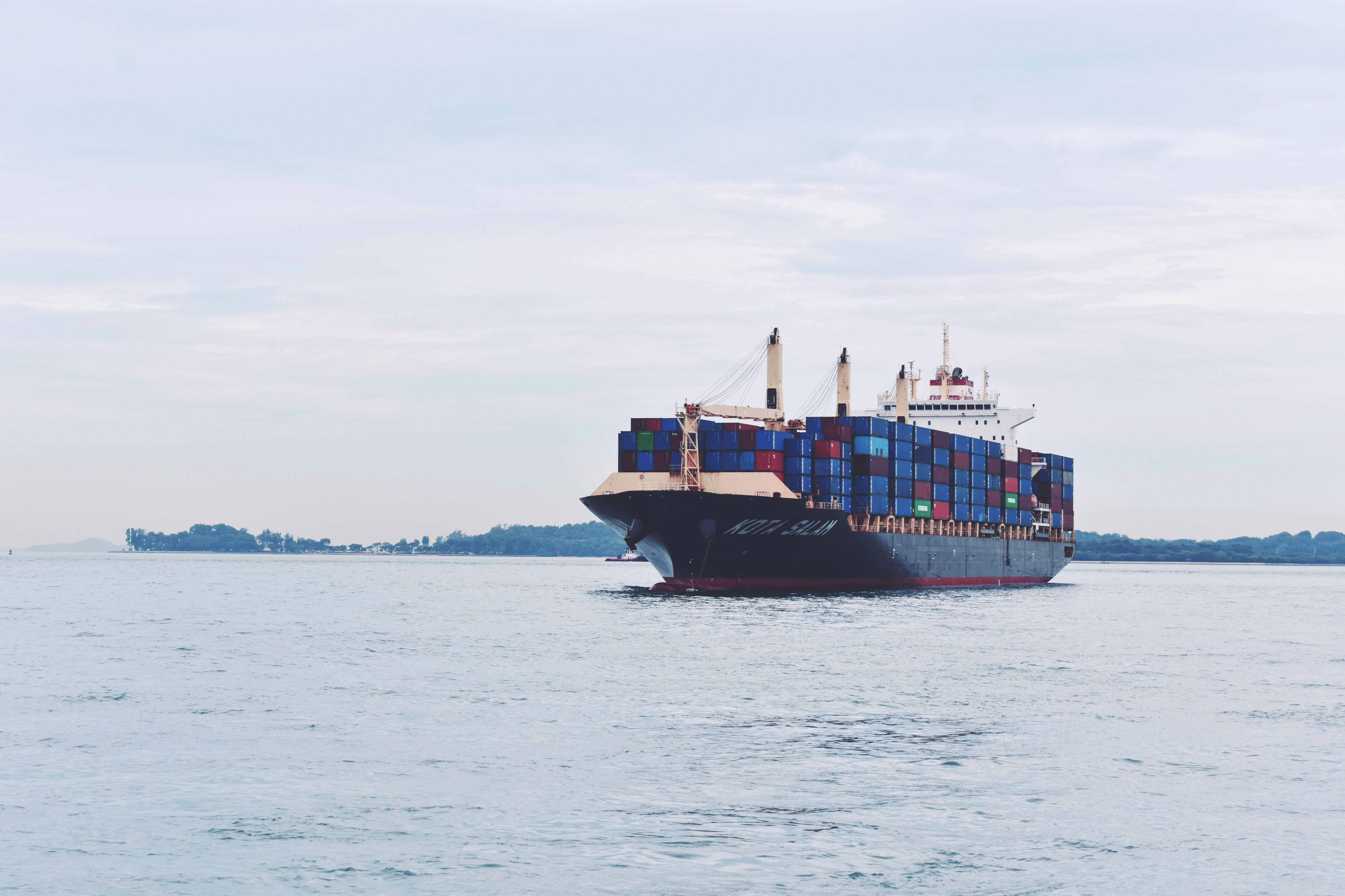 A cargo ship loaded with shipping containers travels through open water.