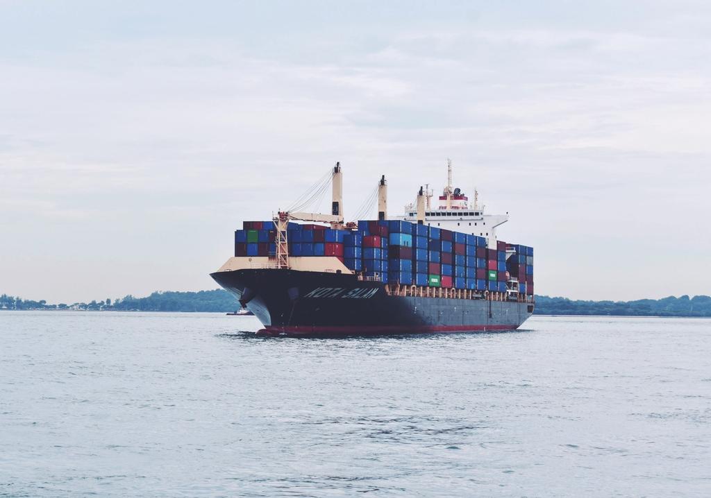 A cargo ship loaded with shipping containers travels through open water.
