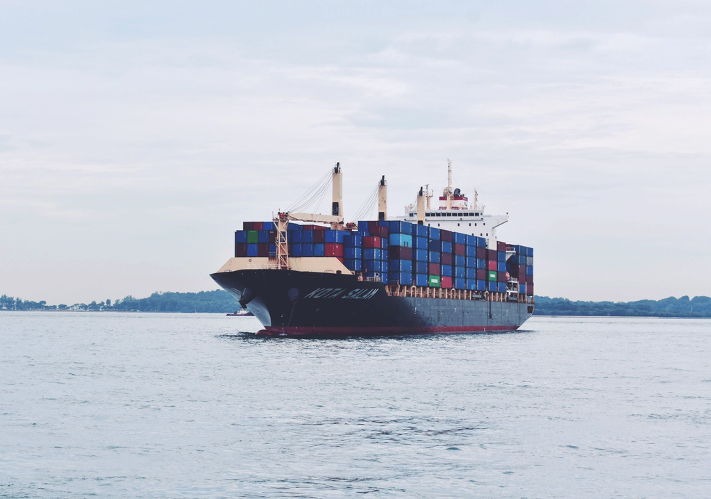 A cargo ship loaded with shipping containers travels through open water.