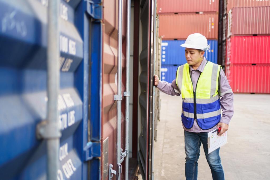 Worker in a hard hat and safety vest inspecting an open shipping container in a yard