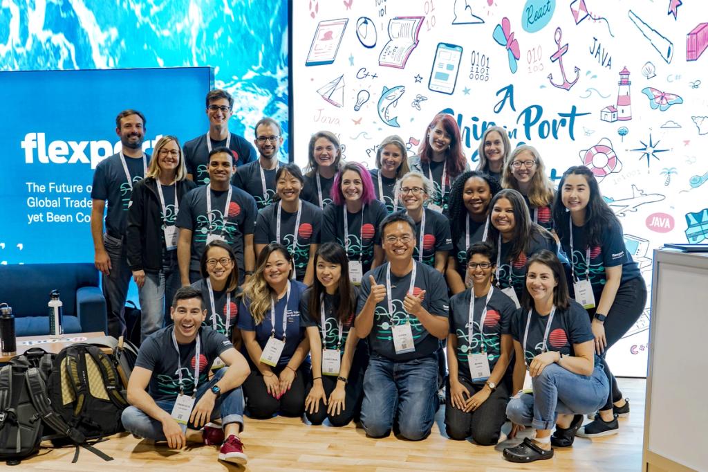 Group of Flexport employees in matching dark T-shirts posing at the Grace Hopper conference booth
