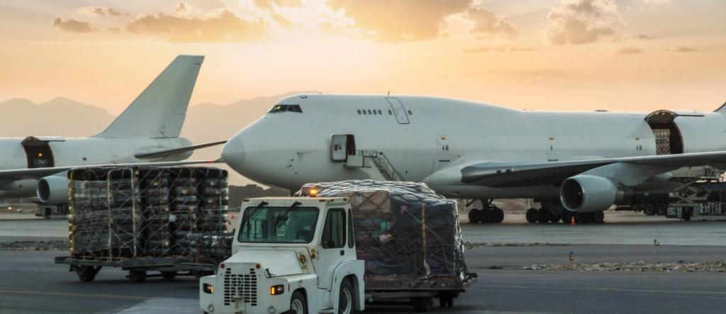 Two white Boeing 747 freighters at dusk with a tug towing palletized air cargo across the tarmac