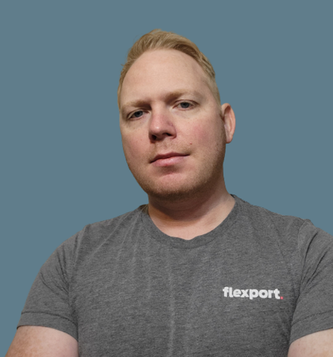 Headshot of a man in a gray Flexport T-shirt against a blue background