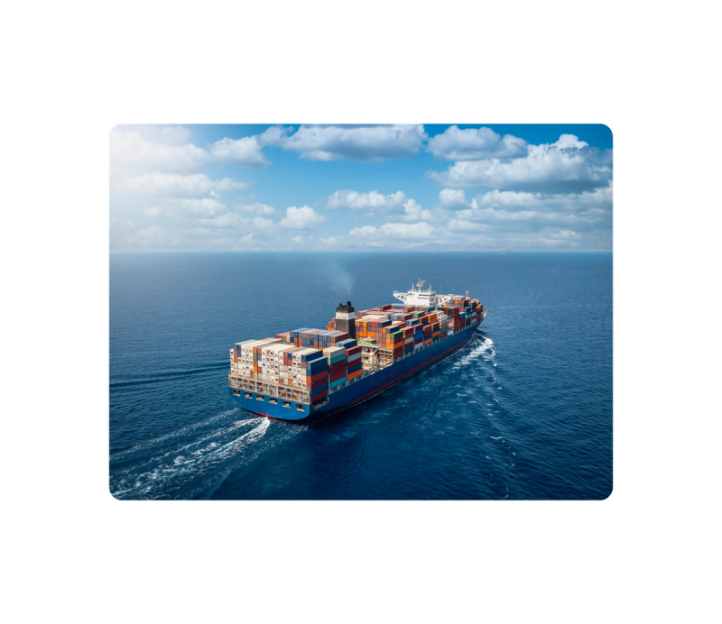 Aerial view of a fully loaded container ship sailing across calm open ocean under blue sky