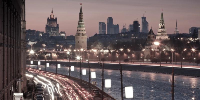 Moscow skyline at dusk with Kremlin towers and a riverside road of light trails