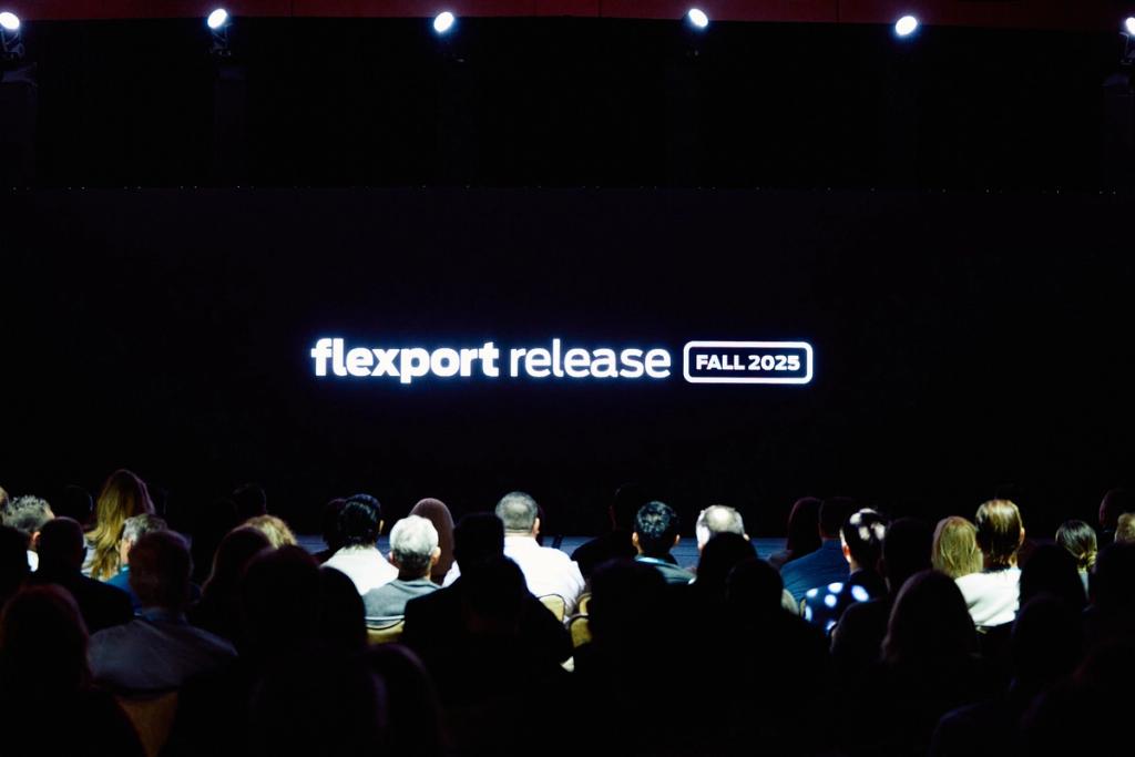 Audience seated before a dark stage screen reading flexport release FALL 2025.