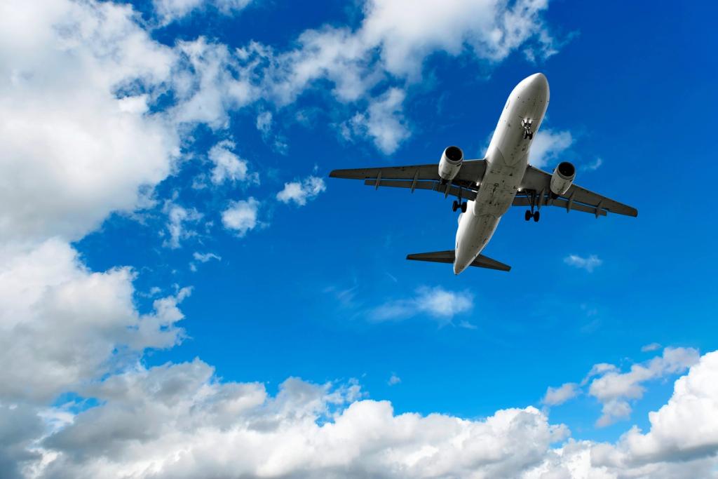White passenger jet airliner flying low against a bright blue sky with scattered white clouds, viewed from below