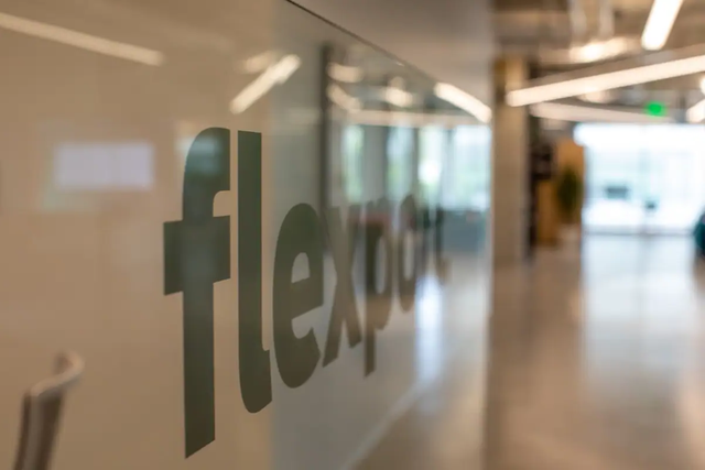 Frosted glass office partition etched with the Flexport wordmark, blurred hallway behind
