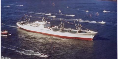 Vintage photo of a large white and red cargo ship surrounded by small boats