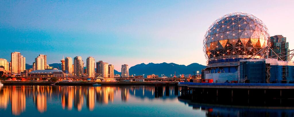 Vancouver waterfront skyline at dusk with the lit geodesic Science World dome reflected in the water