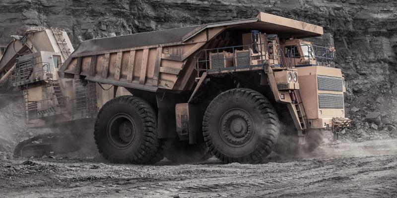 Large haul truck and excavator working at an open-pit mine surrounded by rock walls