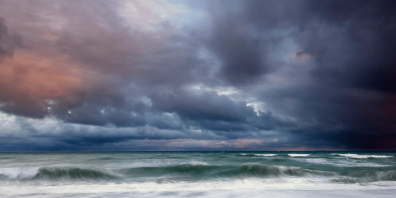 Stormy gray clouds over a choppy sea with breaking waves at the shoreline