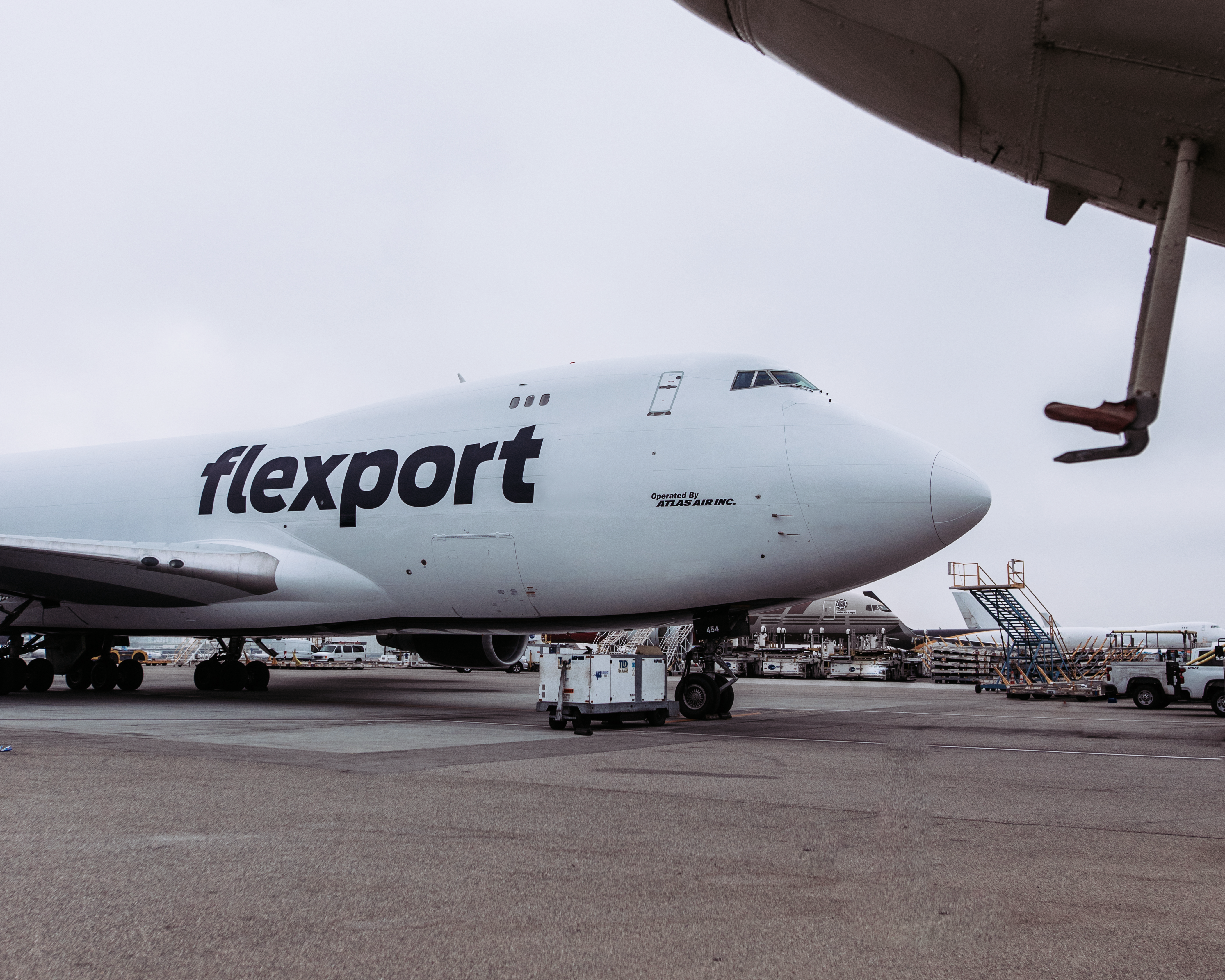 Flexport cargo aircraft parked at airport with ground support equipment nearby.