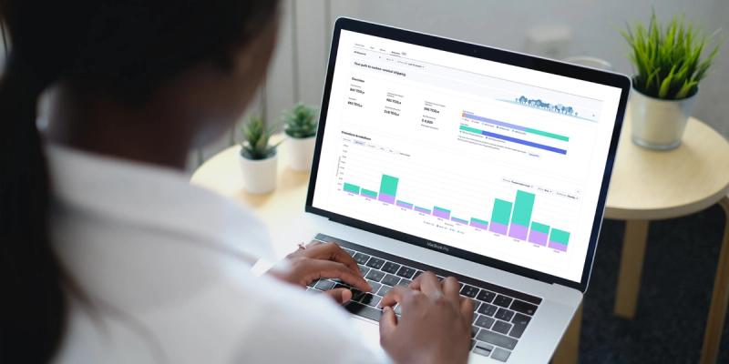 Woman at a laptop viewing a carbon-neutral shipping emissions analytics dashboard