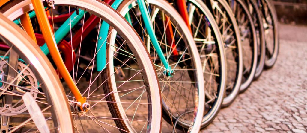 Row of colorful bicycle wheels and frames lined up on a cobblestone street